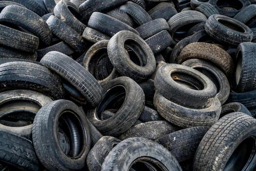wide-rubber-wheel-from-the-auto-lying-on-the-background-of-used-tires-with-light-leaks-in-an-old-plant-old-worn-out-tires-on-an-abandoned-trash-dump-photo